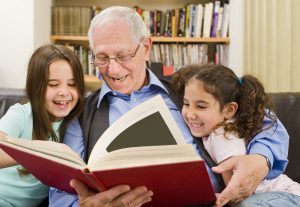 grandfather and grandchildren reading a book